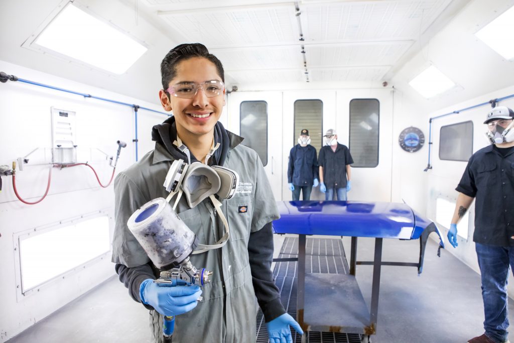 An auto collision repair technology student re-painting part of a car