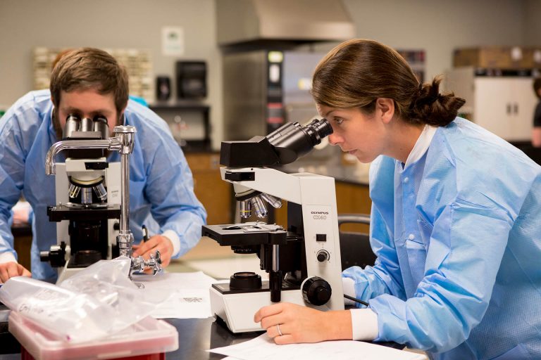 Biological clinical science students using microscopes in a classroom lab