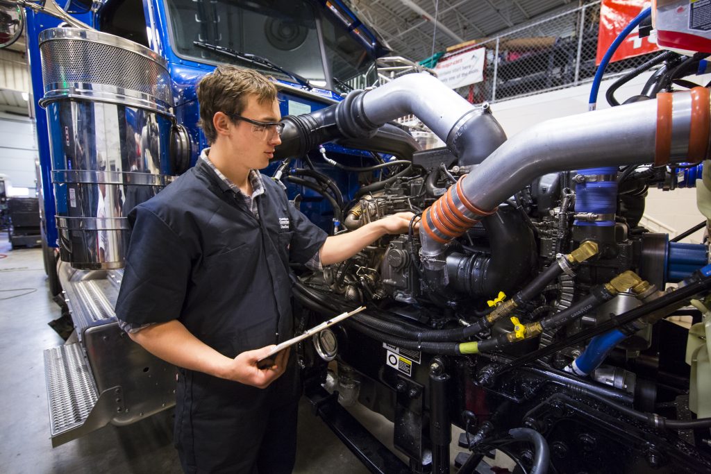 A diesel technology student repairing a diesel engine