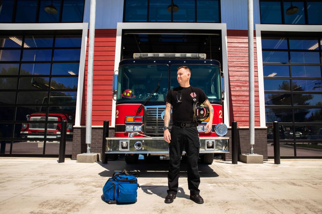 A fire science technology student preparing gear in front of a fire truck