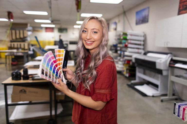 A graphic design technology student looking at color swatches in the OTC Print Shop