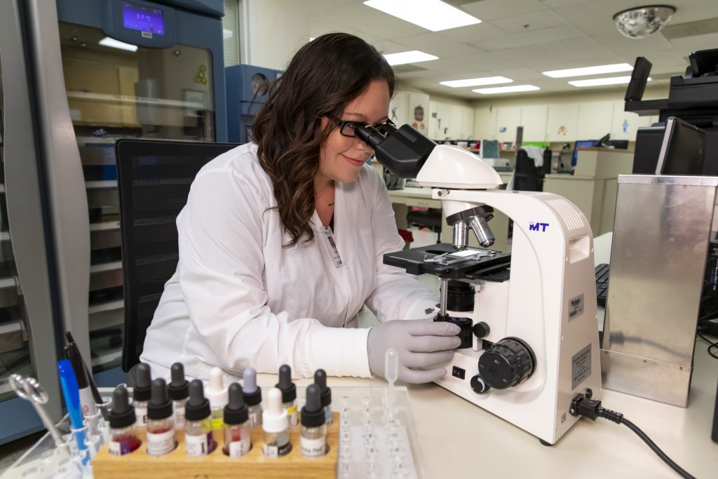 A medical laboratory technician using a microscope