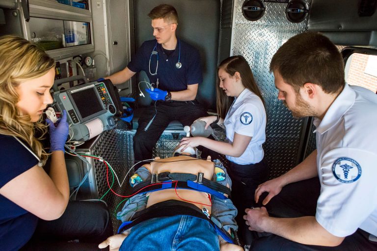 Paramedicine students practicing with a medical dummy in an ambulance simulation