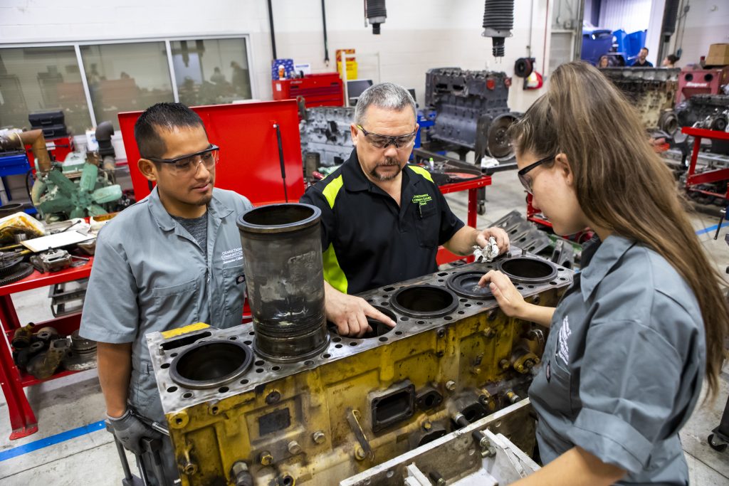 A remanufacturing technology instructor showing students a metal part