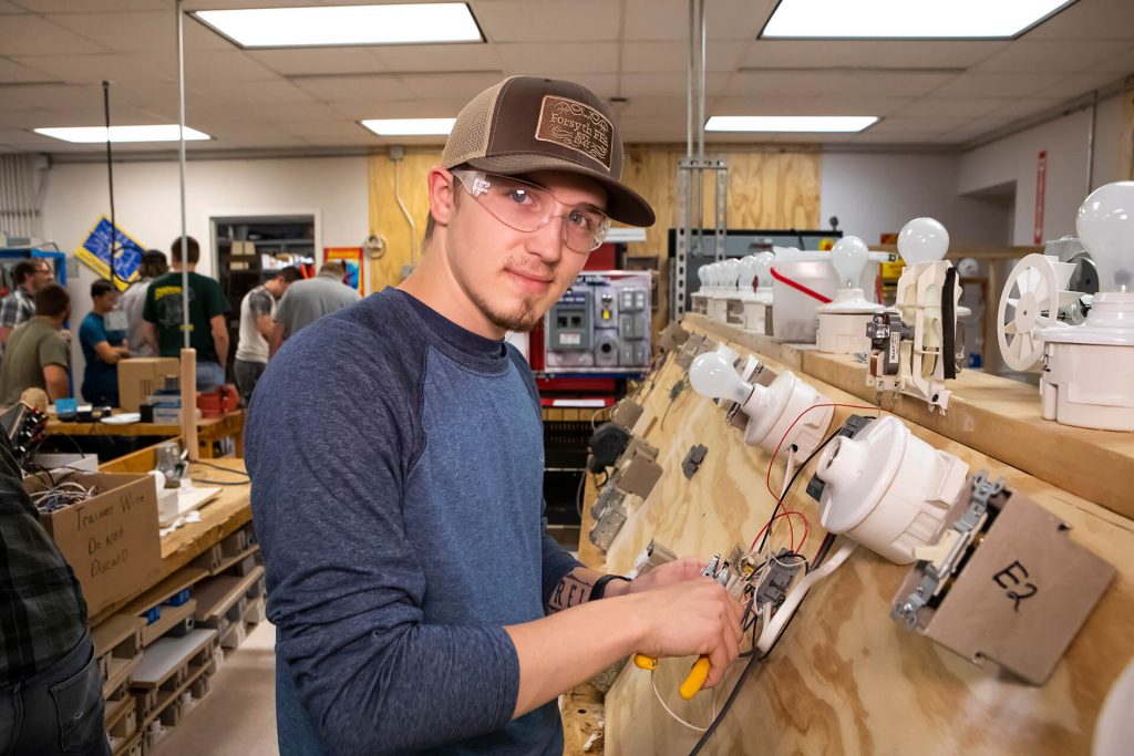 An electrical technician student practicing working on circuitry in a lab