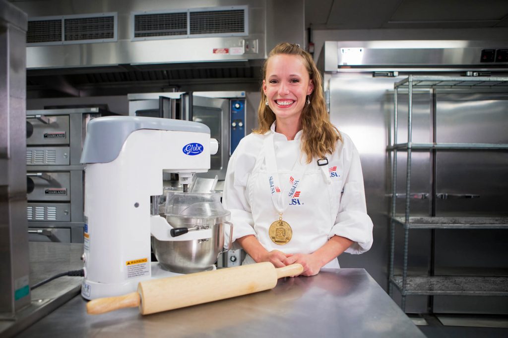 A baking and pastry student using a stand mixer and rolling pin in a kitchen